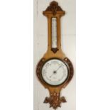 A W Gamage Ltd London, Oak cased, banjo shaped Aneroid barometer, with thermometer, with carved