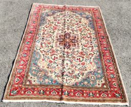 Cream ground rug with central medallion, within red border, 135 cm wide, 210 cm length, in good