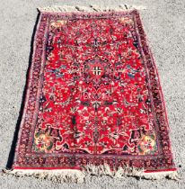 Red ground with all over pattern rug with long fringe, 110 cm wide, 175 cm length, in good