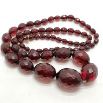 Strand of facetted cherry bakelite amber -70cm & largest bead 3cm across & 71g total weight &