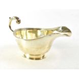 A George V hallmarked silver sauce boat with egg and dart border and scroll handle, S