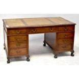 A mahogany nine-drawer twin pedestal desk with brush in slides, tan leather inserts to the top,