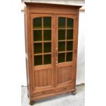 An early 20th century oak two-door cabinet, the moulded cornice above a pair of part glazed doors