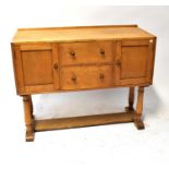 HEALS OF LONDON; an oak sideboard with a pair of drawers flanked by cupboard doors, on turned