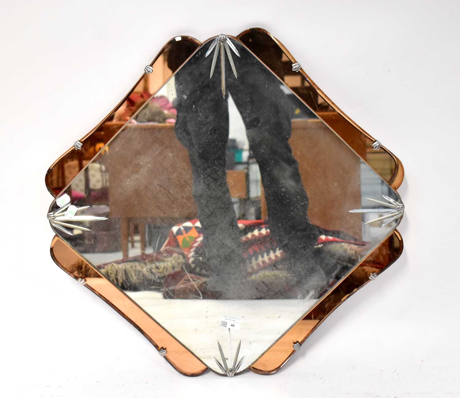 A 1930s wall mirror of shaped square form with amber glass border and etched starburst to the