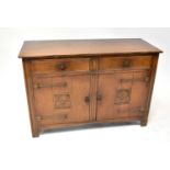 An Arts & Crafts style oak sideboard with two drawers over two cabinets carved with flowerhead