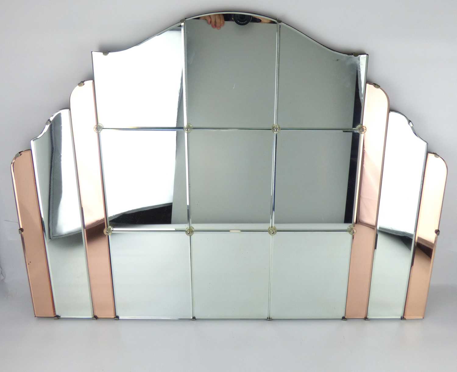 An Art Deco shaped clear and copper toned panelled wall mirror, the central section of six bevel