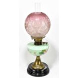 A Victorian oil lamp, the cranberry and clear shade with floral decoration above hand painted opaque