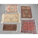 Four assorted small hand knotted woollen rugs and a machine made example (5).