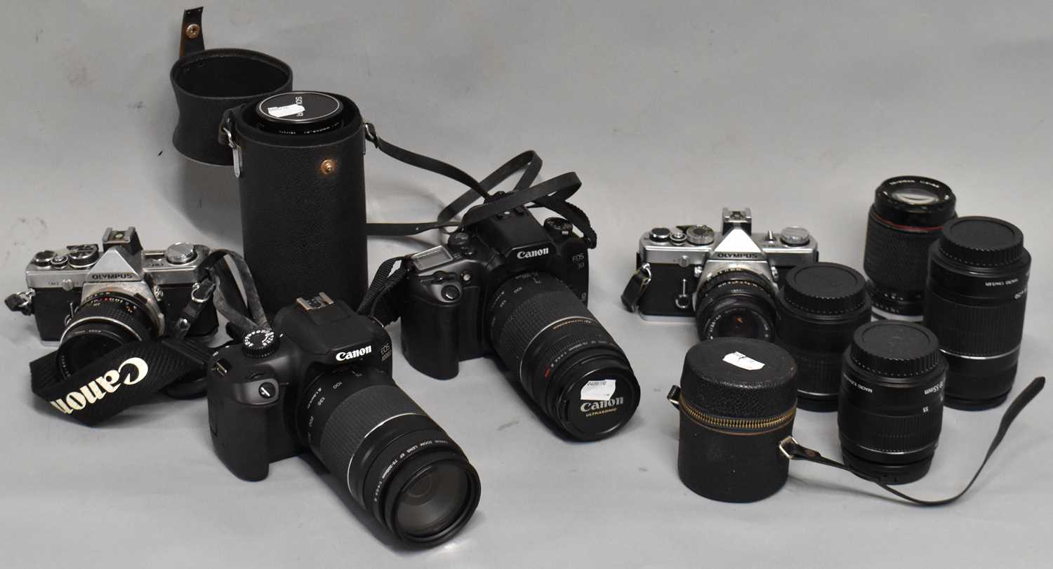 A group of cameras including a Canon EOS30, a Canon EOS4000D, various additional lenses and an
