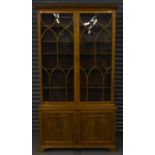 A late 19th century walnut bookcase, the upper section with Gothic style glazing above a pair of