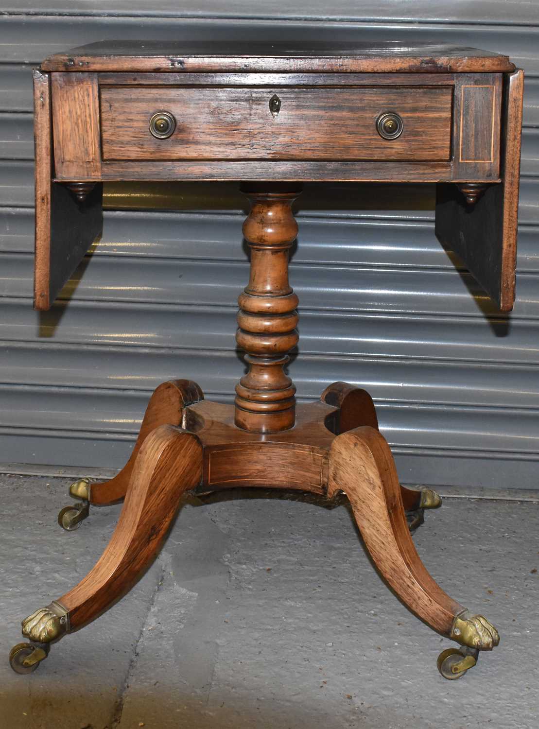 An early 19th century rosewood drop leaf side table with single frieze drawer on turned column and