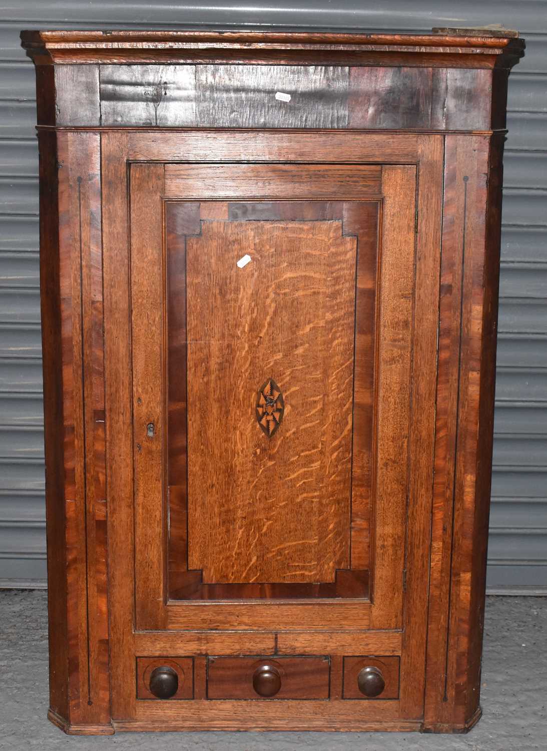 An early 19th century oak and mahogany crossbanded straight front wall hanging corner cupboard