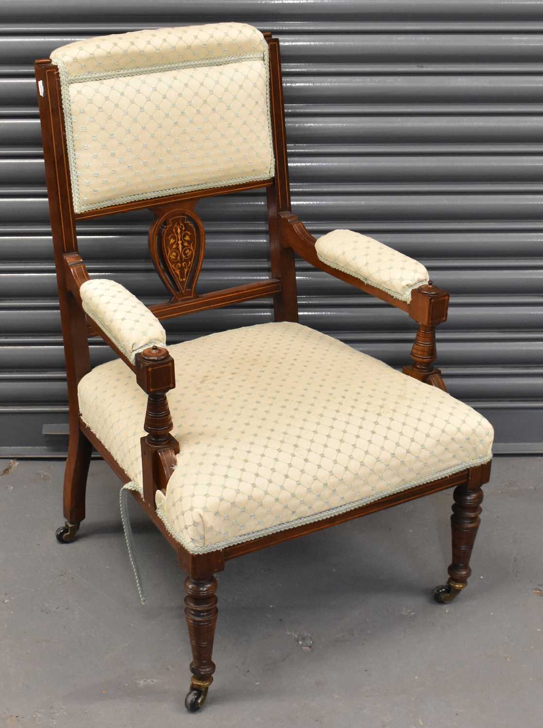 An Edwardian inlaid mahogany upholstered open armchair on ring turned supports.