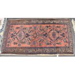 A hand knotted woollen red ground rug, 185 x 104cm.