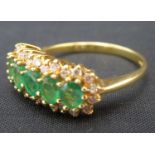 An 18ct gold emerald and diamond cluster ring, the central band of five claw set oval emeralds