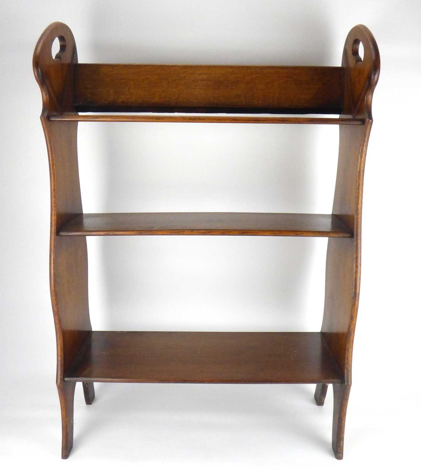 An Arts & Crafts style oak floorstanding bookcase with three shelves and side handle cut-