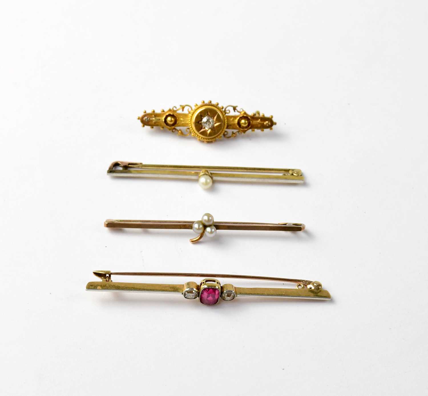 Four Victorian and Edwardian bar brooches comprising a 15ct yellow gold bar brooch with central