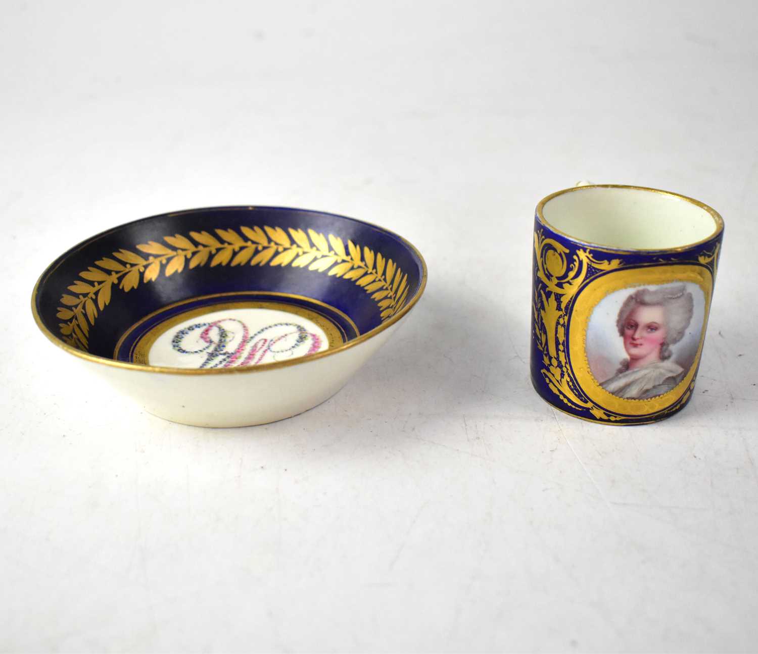 SÈVRES; a circa 1754 coffee cup and saucer, with cobalt blue ground and vignette of a lady in 18th