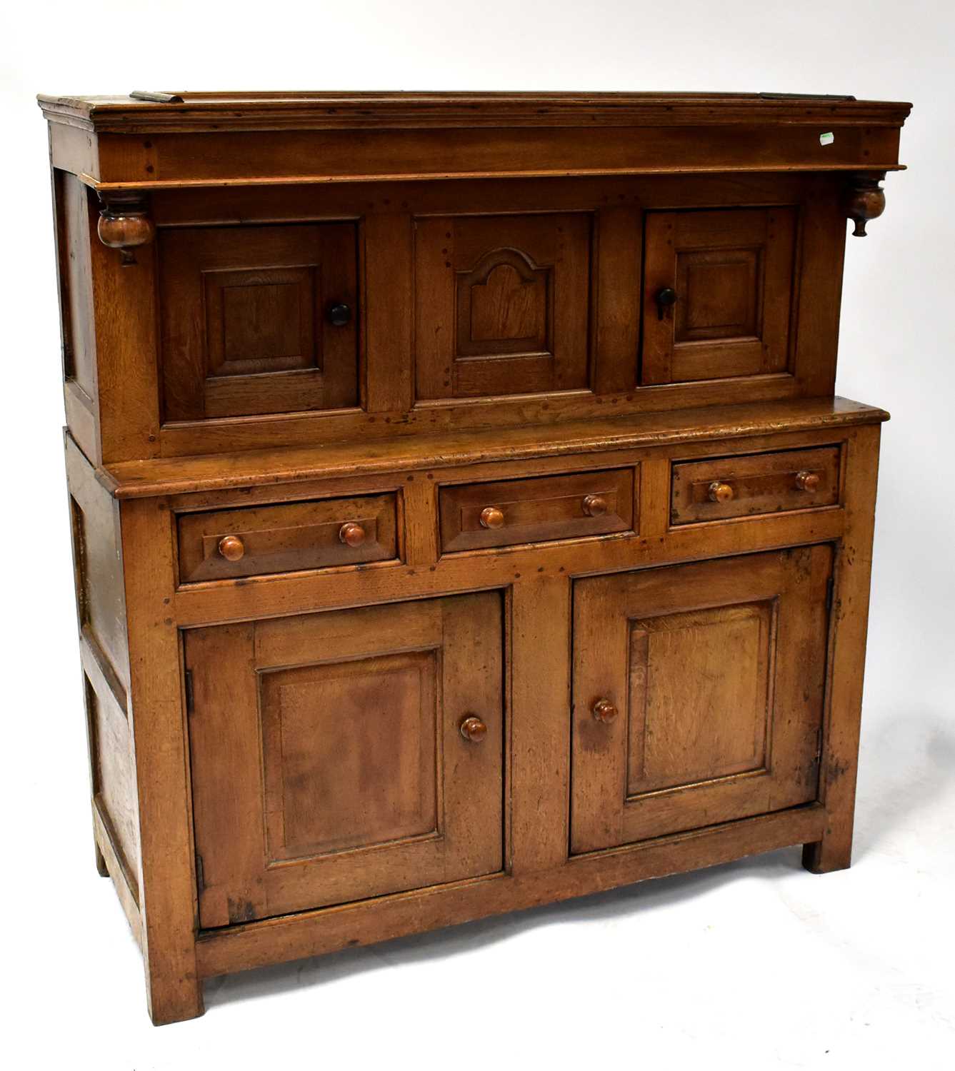 An 18th century oak court cupboard, the upper section with three panelled doors, above a break front