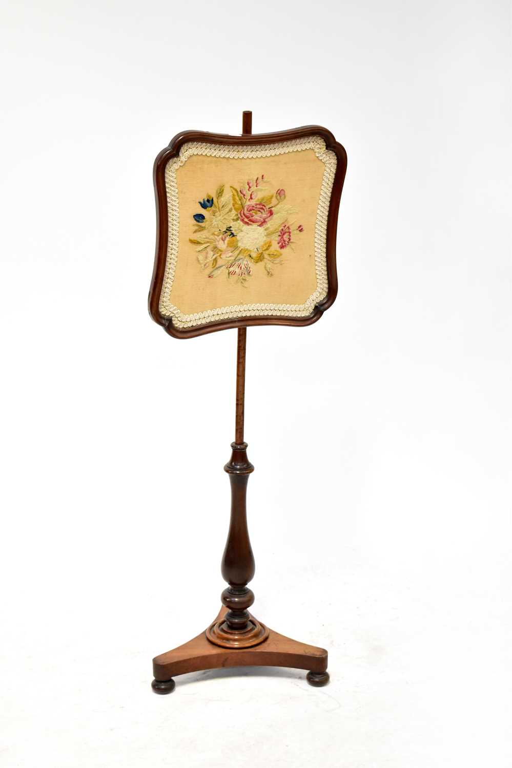 A Victorian mahogany adjustable pole screen decorated with a needlework panel depicting flowers,