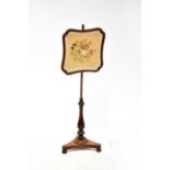 A Victorian mahogany adjustable pole screen decorated with a needlework panel depicting flowers,