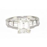 A platinum and diamond solitaire ring, the principal emerald step cut stone weighing 3.04ct, with