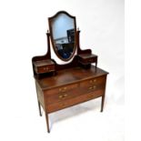 An Edwardian crossbanded mahogany dressing chest with shield-shaped mirror to the back flanked by