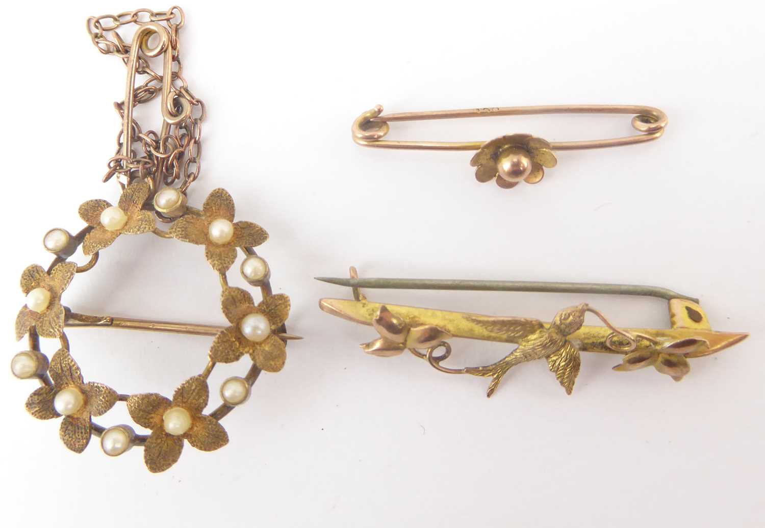 Three brooches comprising a 9ct gold bar brooch with swallow and leaves, length 3.6cm, a 9ct gold