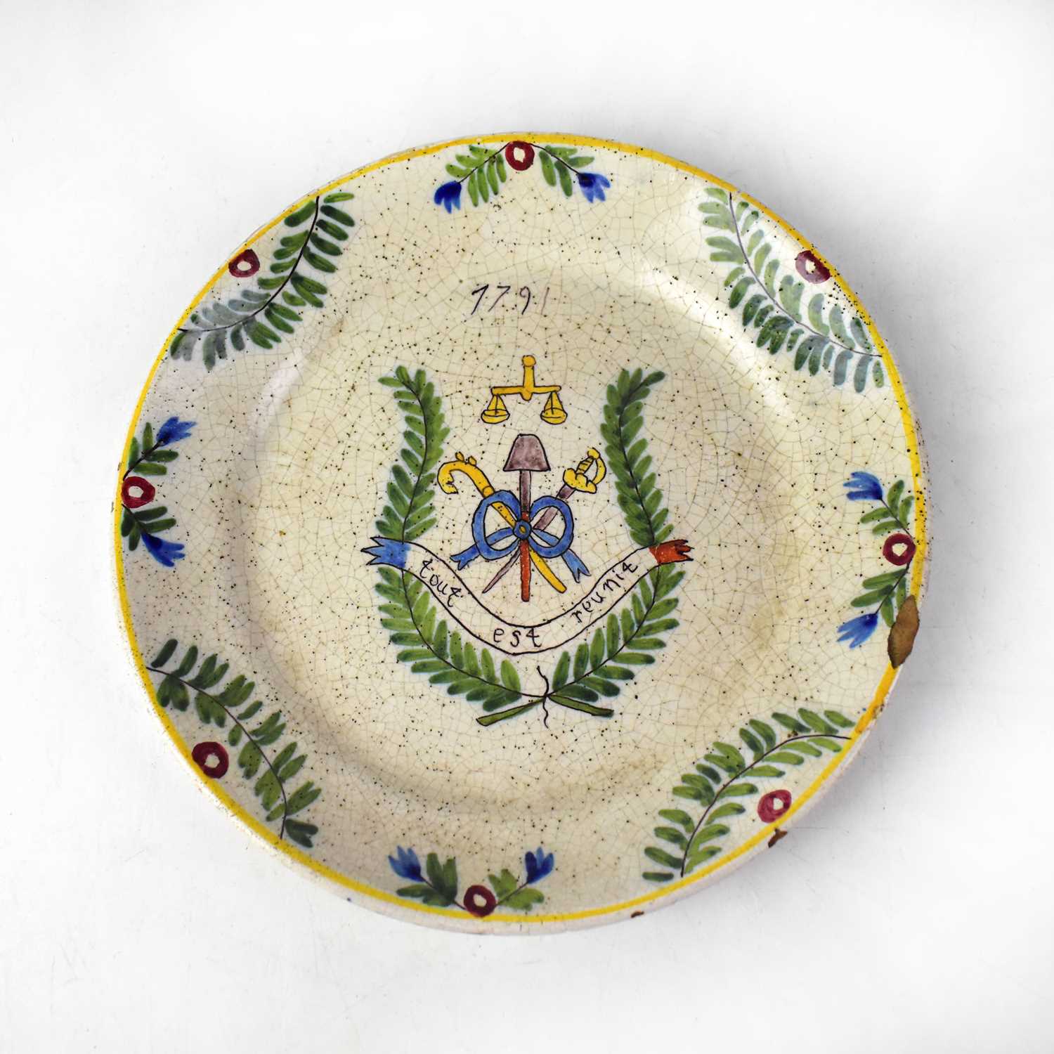 A French faience commemorative plate with naive hand painted border of flora and foliage, central