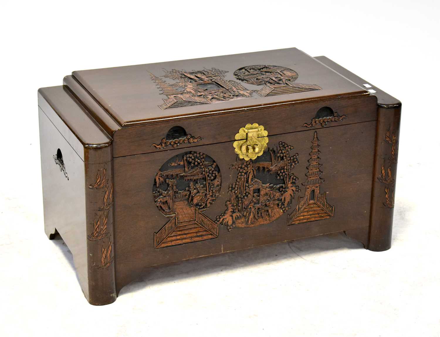 An Eastern camphorwood chest with profusely carved top depicting figures in a pagoda landscape, with