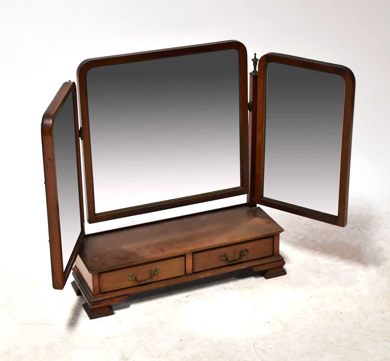 An Edwardian mahogany triptych dressing table mirror with two base drawers, raised on ogee bracket