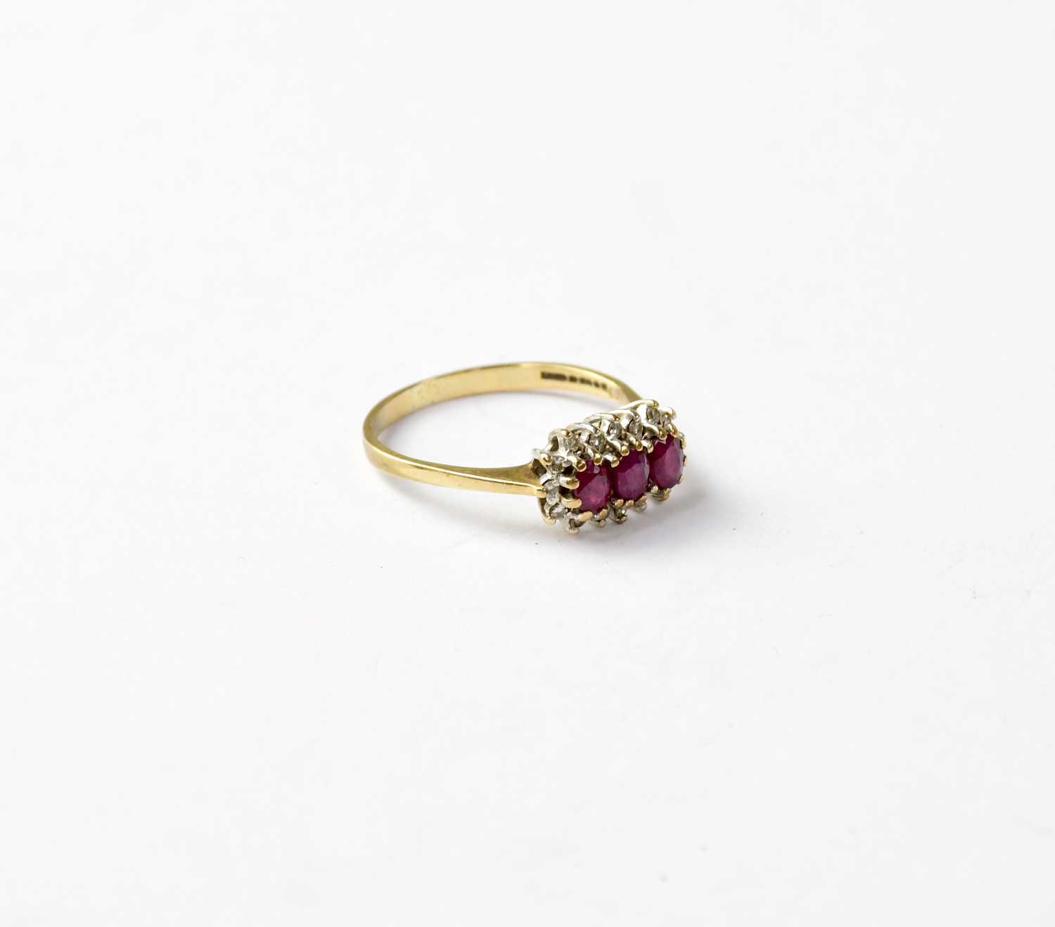 A vintage 9ct gold ruby and diamond cluster ring, the three claw set oval rubies within a border