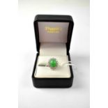 An 18ct white gold floral set ring, the central oval cabochon jade stone with fourteen diamond