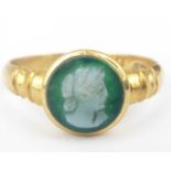 A vintage 18ct gold intaglio ring in the Roman style with a bezel set white cameo bust on a green