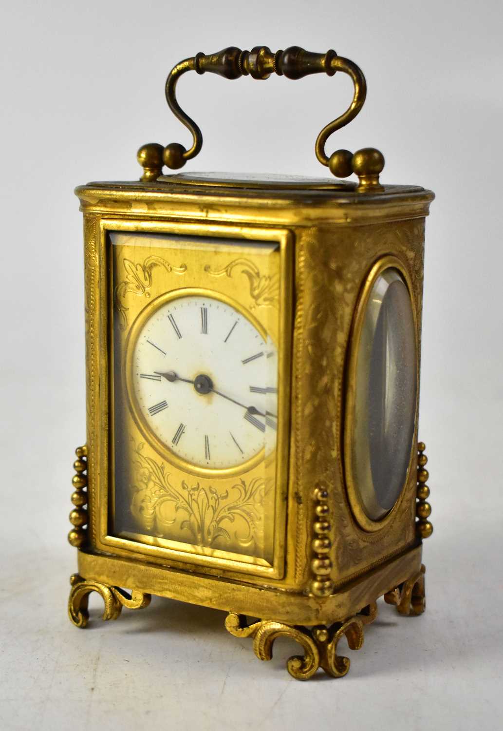 A brass cased carriage clock, the enamelled dial set with Roman numerals, within an engraved