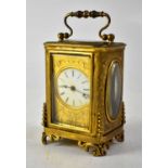 A brass cased carriage clock, the enamelled dial set with Roman numerals, within an engraved