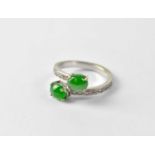 An 18ct White gold ring of crossover design with two jade cabochon stones and small diamonds set