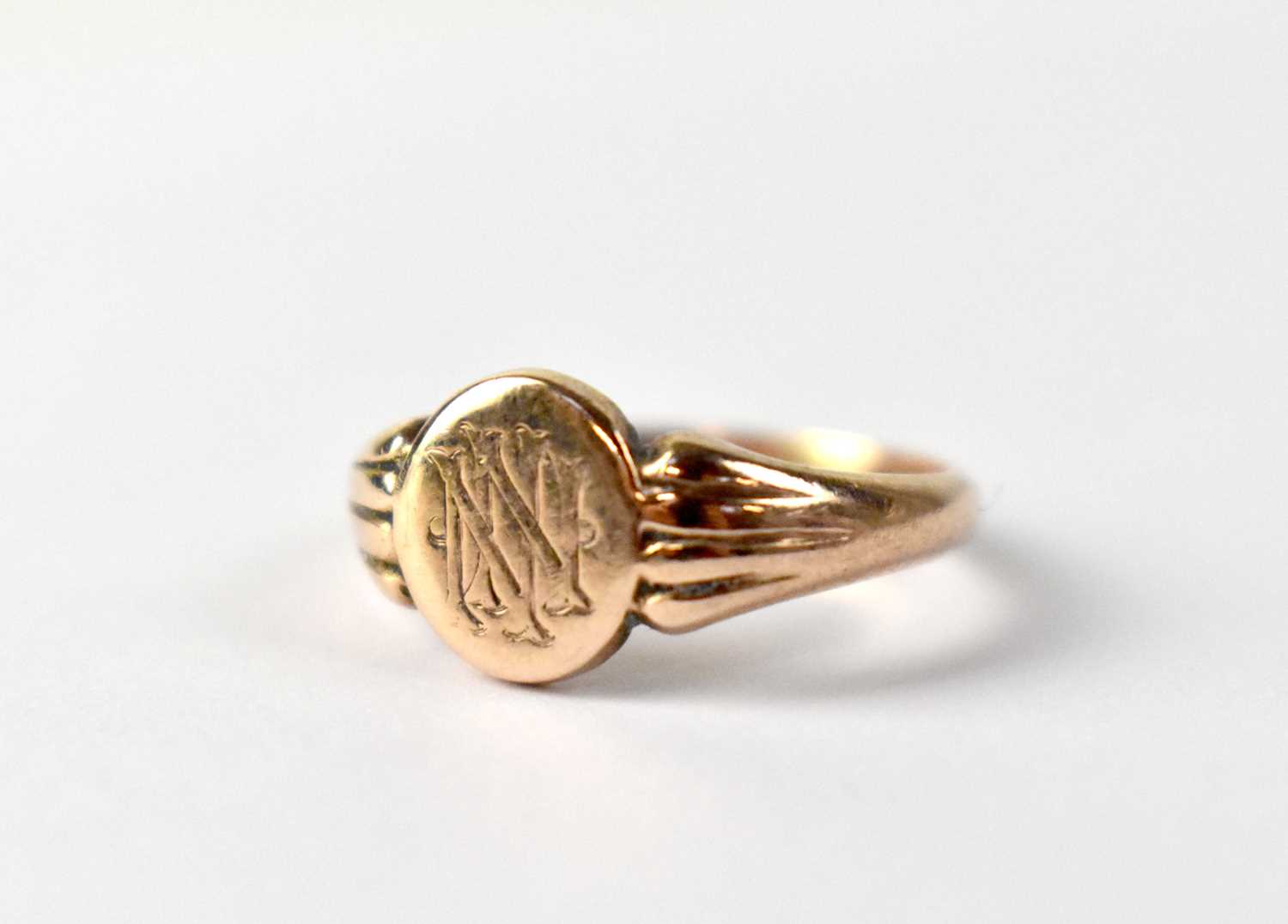 A vintage 9ct rose gold signet ring, the circular table with entwined initials 'NN', to fan-shaped