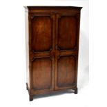 A mid-20th century mahogany wardrobe, stepped frieze above twin doors with panel moulding to