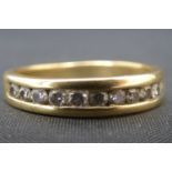 A modern 18ct gold half eternity ring with thirteen channel set brilliant cut diamonds, size M,