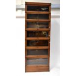 GLOBE-WERNICKE; an early 20th century seven-tier oak bookcase with lift-up glass doors, to stepped