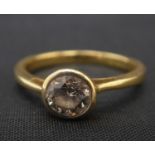 An 18ct gold diamond solitaire ring with central brilliant cut diamond in a bezel mount, stated