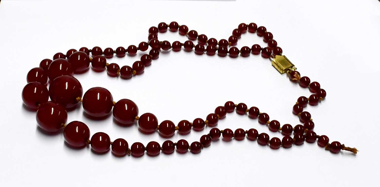 Two cherry amber-style necklaces, one with oval graduated beads, the other with circular beads.