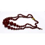 Two cherry amber-style necklaces, one with oval graduated beads, the other with circular beads.