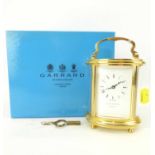 GARRARD, LONDON; a modern brass oval carriage clock with bevel edge glazed panels, the white dial