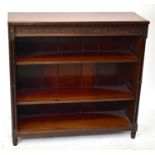 An early 20th century mahogany dwarf open fronted bookcase with blind fret decoration to the top
