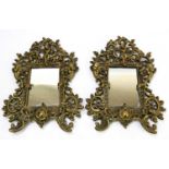 A pair of decorative gilt brass wall mirrors, decorated with cherubs playing the pipes, with