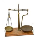 A set of brass balance/beam scales, raised on rectangular plinth, width 50cm.