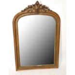 A late 19th century gilt plaster and wood wall mirror of arched form with applied open shell and